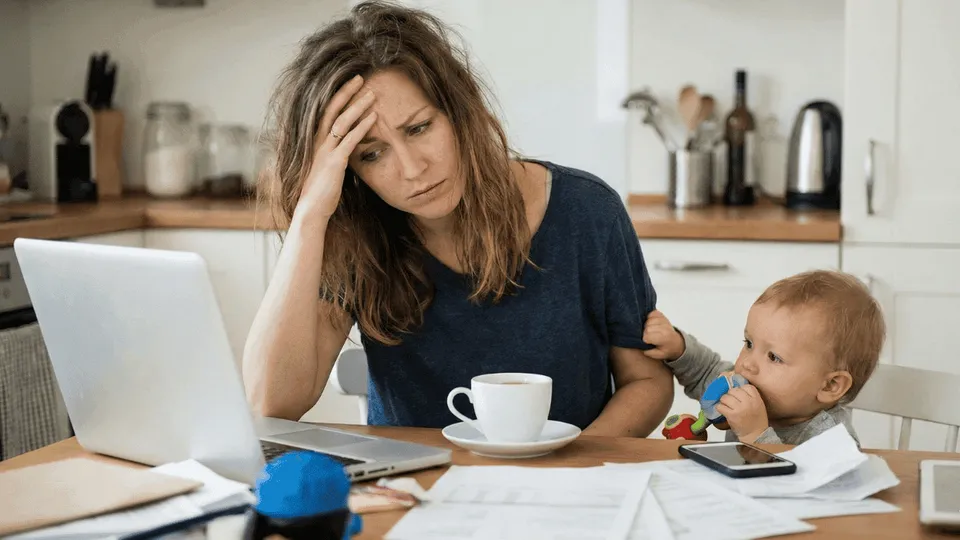 Maman entrepreneure fatiguée face à son ordinateur illustrant la culpabilité mampreneure.