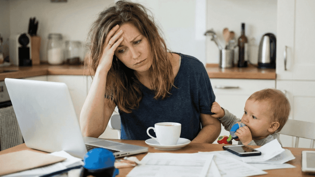 Maman entrepreneure fatiguée face à son ordinateur illustrant la culpabilité mampreneure.